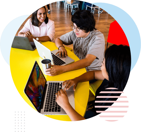 Three people sit at a yellow table, working on laptops and conversing. One person holds a coffee mug. The environment suggests a casual and collaborative workspace with modern decor. CodersLink 2024.